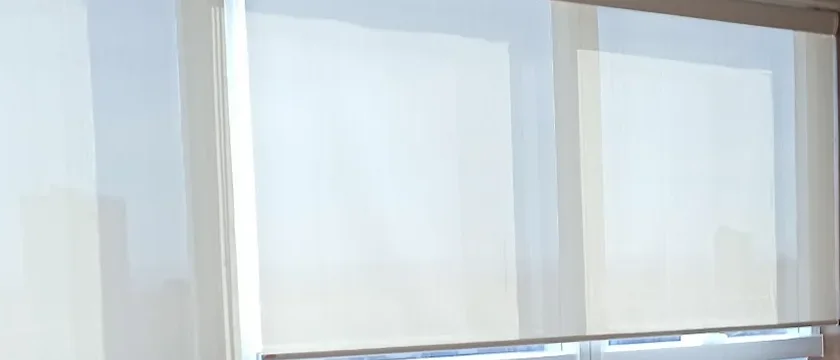 A persiana da sala do Dr. Marcus, com a luz da cidade atravessando o tecido